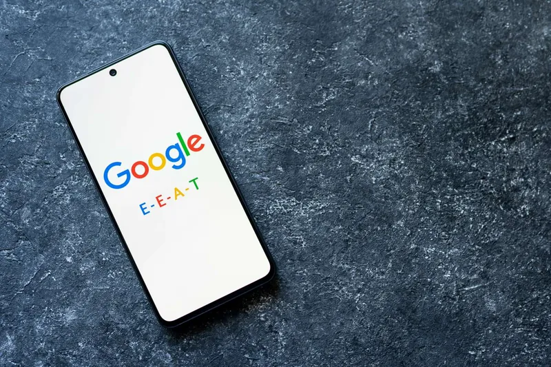 Smartphone posé sur une surface sombre, affichant le logo Google et le sigle E-E-A-T