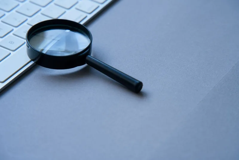Loupe posée à côté d'un clavier sur un bureau bleu