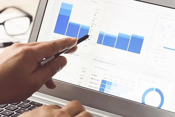 Stylo pointant un tableau de bord d'analytique sur l'écran d'un ordinateur portable